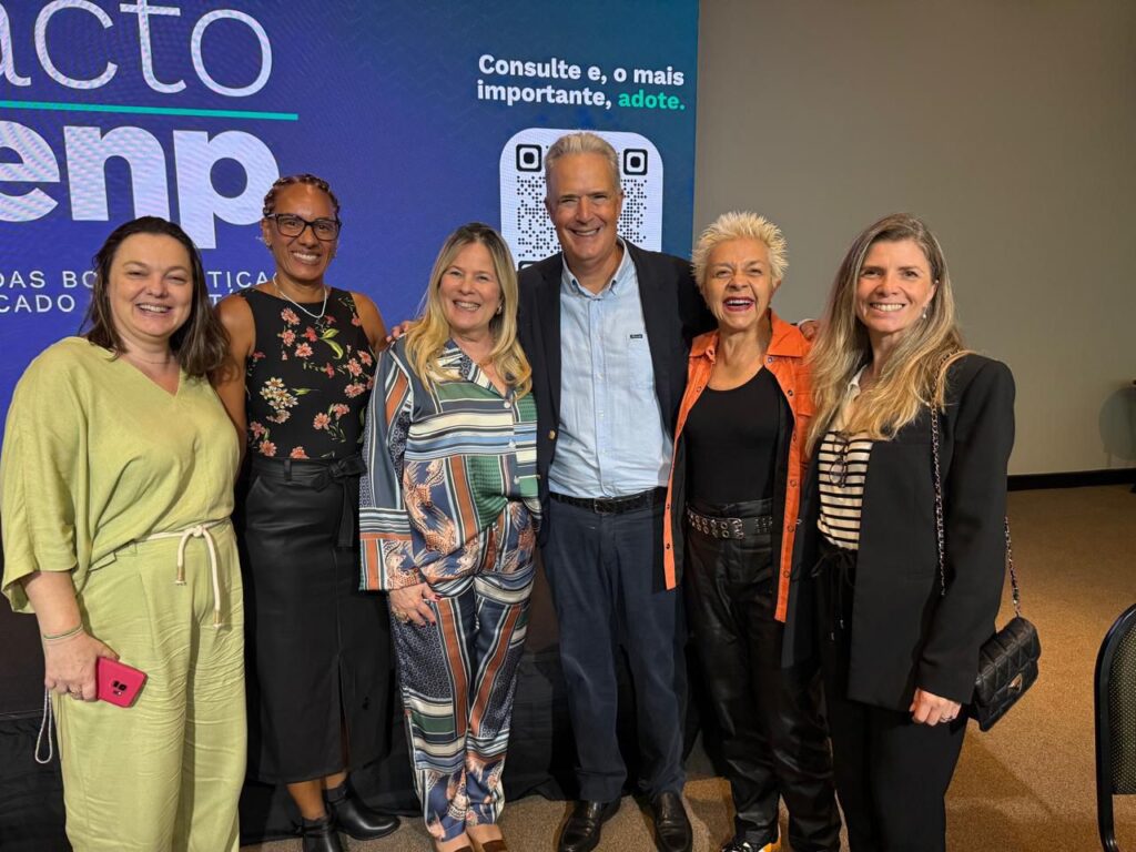 GRupo de pessoas representantes de instituições de comunicação reunidas diante de uma tela azul na cerimônia de lançamento do Pacto Cenp